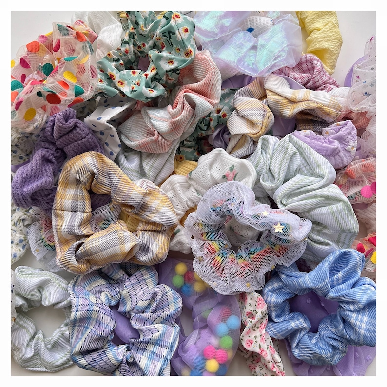 May include: A collection of colorful hair scrunchies in various patterns and textures, including plaid, floral, and mesh. The scrunchies are arranged in a pile, showcasing a variety of styles and colors.