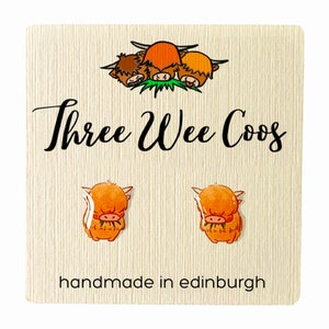 May include: A pair of earrings featuring a cute cartoon Highland cow design. The earrings are handmade in Edinburgh, Scotland. The card reads "Three Wee Coo's".