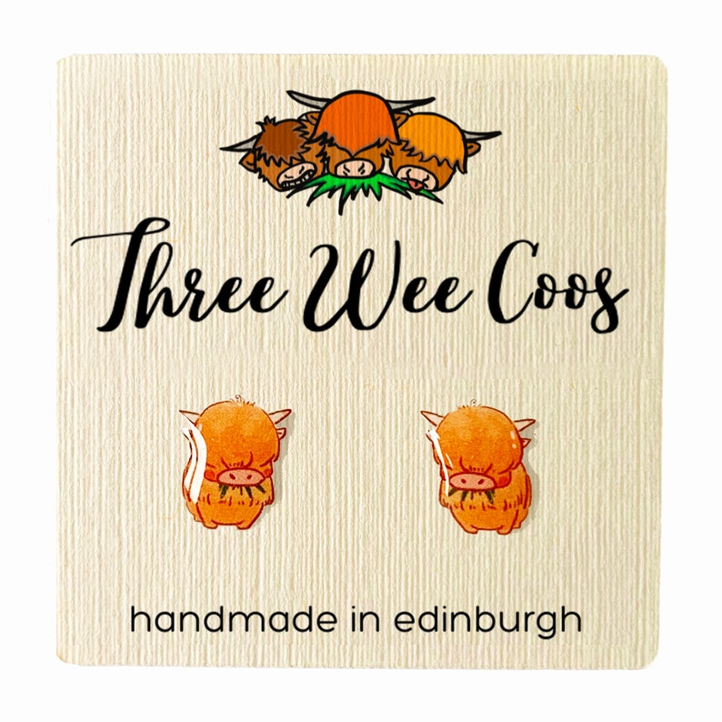 May include: A pair of earrings featuring a cute cartoon Highland cow design. The earrings are handmade in Edinburgh, Scotland. The card reads "Three Wee Coo's".