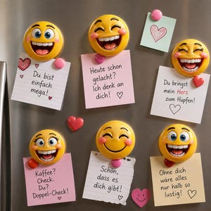 Könnte beinhalten: Eine Sammlung gelber Emoji-Magnete mit lächelnden Gesichtern, die an einem Kühlschrank befestigt sind. Jeder Magnet hält eine kleine rosa oder weiße Notiz mit handgeschriebenem deutschem Text und Herzillustrationen. Die Notizen vermitteln positive Botschaften.