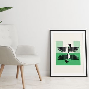 Peut inclure: Une illustration g&eacute;om&eacute;trique en noir et blanc d'un huard avec des rayures vertes et blanches en arri&egrave;re-plan. L'image est encadr&eacute;e en noir et accroch&eacute;e &agrave; un mur blanc.