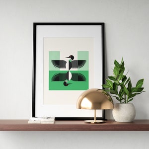 Peut inclure: Une impression encadr&eacute;e d'un design g&eacute;om&eacute;trique de huard noir et blanc sur fond vert. L'impression est expos&eacute;e sur une &eacute;tag&egrave;re avec une lampe dor&eacute;e et une plante en pot.
