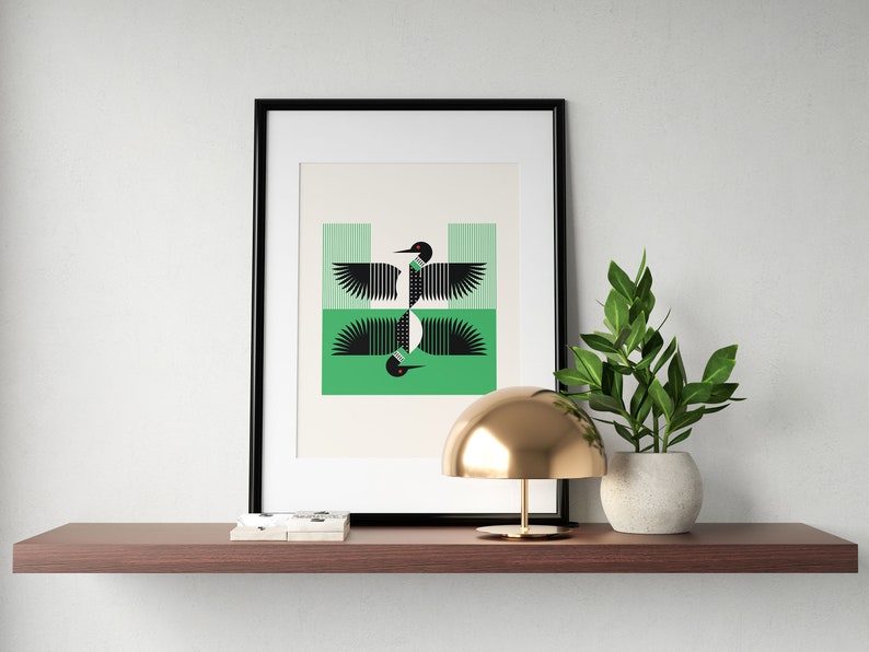 Peut inclure: Une impression encadr&eacute;e d'un design g&eacute;om&eacute;trique de huard noir et blanc sur fond vert. L'impression est expos&eacute;e sur une &eacute;tag&egrave;re avec une lampe dor&eacute;e et une plante en pot.