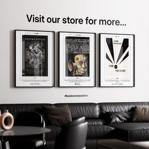 three framed posters on a wall, with a black leather couch and a coffee table in the foreground.