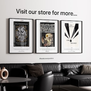 three framed posters on a wall, with a black leather couch and a coffee table in the foreground.