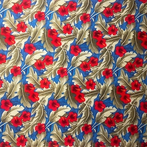 May include: A vibrant fabric featuring a repeating pattern of red hibiscus flowers and large, light brown leaves against a textured blue background. The design evokes a tropical or Hawaiian theme, suitable for apparel or home decor.