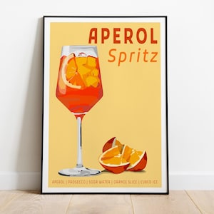 May include: A framed poster featuring a graphic illustration of an Aperol Spritz in a stemmed glass with an orange slice and ice cubes. The background is yellow with the text Aperol Spritz and a list of ingredients: Aperol, Prosecco, soda water, orange slice, cubed ice.