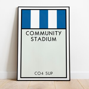 May include: A framed print with a blue and white striped design. The print says "COMMUNITY STADIUM" and "CO4 5UP".
