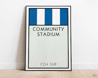 May include: A framed print with a blue and white striped design. The print says "COMMUNITY STADIUM" and "CO4 5UP".