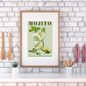 May include: A vintage-style poster with the word "MOJITO" in green text. The poster features a green and white illustration of a mojito cocktail in a tall glass with lime wedges and mint leaves. The text "WHITE RUM, SUGAR, FRESH MINT, FRESH LIME, SODA WATER" is printed below the illustration.