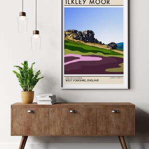 May include: A minimalist poster with a graphic illustration of Cow and Calf Rocks in Ilkley Moor, West Yorkshire, England. The poster has a beige background with black text and a white border.