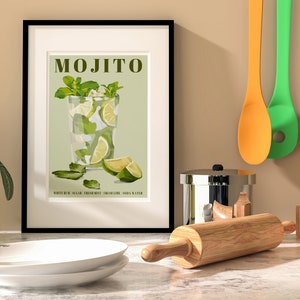 May include: A framed poster with a green background and a drawing of a mojito cocktail. The text "MOJITO" is in brown letters at the top of the poster. The text "WHITE RUM, SUGAR, FRESH MINT, LIME JUICE, SODA WATER" is at the bottom of the poster.