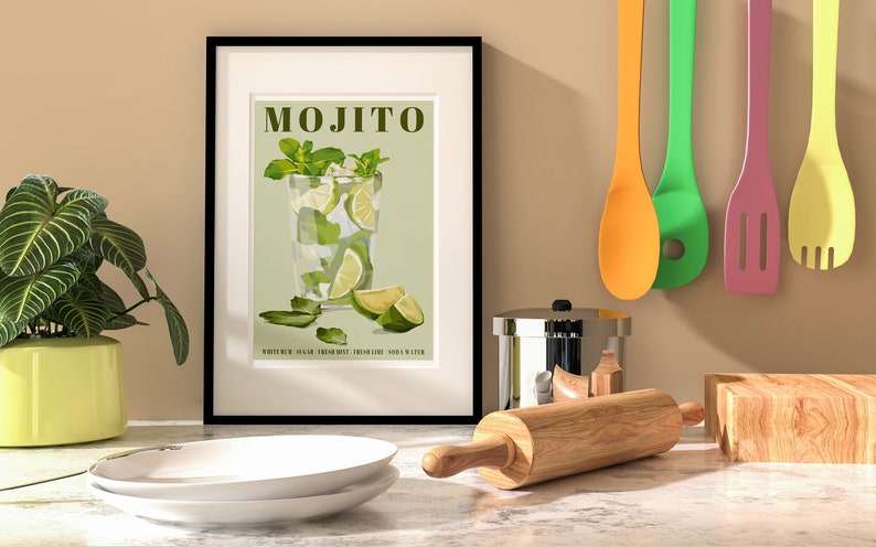 May include: A framed poster with a green background and a drawing of a mojito cocktail. The text "MOJITO" is in brown letters at the top of the poster. The text "WHITE RUM, SUGAR, FRESH MINT, LIME JUICE, SODA WATER" is at the bottom of the poster.