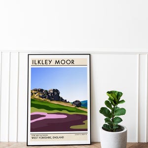 May include: A minimalist poster with a black frame featuring a landscape illustration of Cow and Calf Rocks in Ilkley Moor, West Yorkshire, England. The poster has a blue sky, green hills, and purple heather.