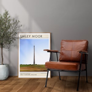 May include: A framed print of a minimalist illustration of a tall tower with the text "Emley Moor" and "Emley Moor Transmitter, West Yorkshire, England" at the bottom.