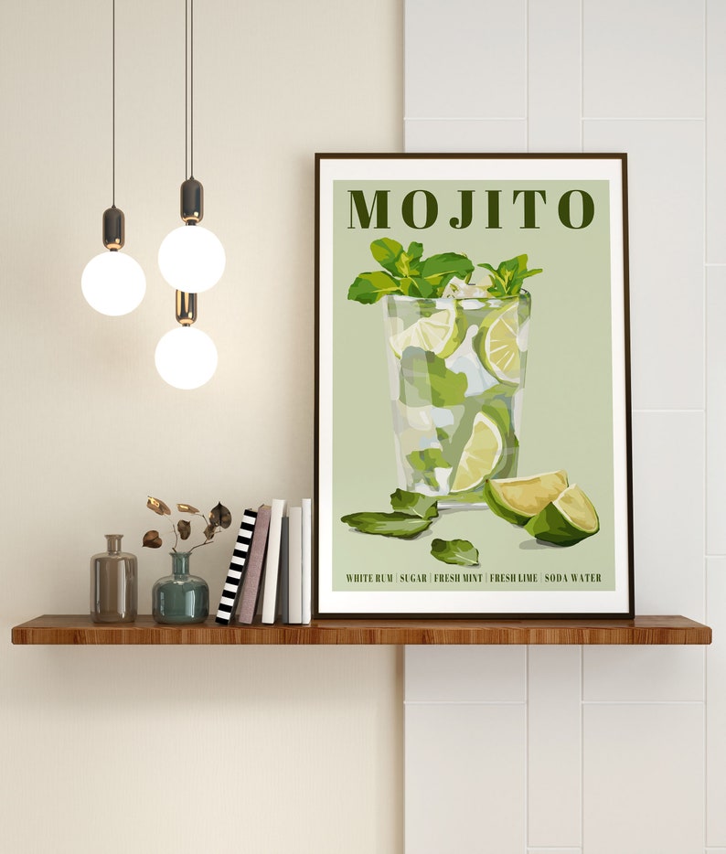 May include: A framed print with a green background and a glass of mojito with lime wedges and mint leaves. The text "MOJITO" is at the top of the print. The text "WHITE RUM | SUGAR | FRESH MINT | FRESH LIME | SODA WATER" is at the bottom of the print.