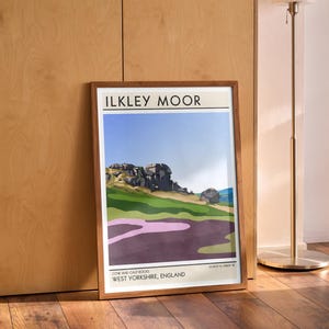 May include: A framed print of a landscape scene with a mountain range in the background. The print is titled "Ilkley Moor" and includes the text "Cow and Calf Rocks, West Yorkshire, England".