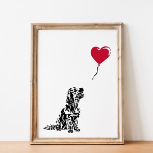 May include: A black and white illustration of a dog looking up at a red heart-shaped balloon. The image is framed in a light wood frame.