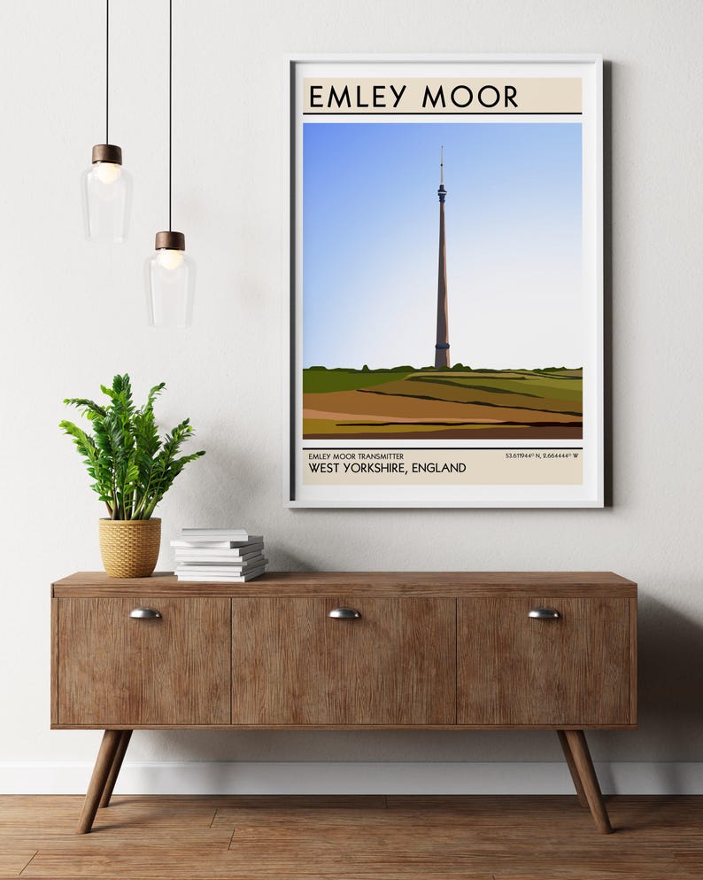 May include: A minimalist poster with a brown background and white text that reads "EMLEY MOOR". The poster features a stylized illustration of a tall, slender tower against a blue sky and green hills. The text "EMLEY MOOR TRANSMITTER WEST YORKSHIRE, ENGLAND" is printed below the illustration.
