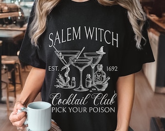 May include: Black t-shirt with a white graphic design featuring cocktail glasses, bottles, and the text "Salem Witch Cocktail Club, Pick Your Poison, Est. 1692." The design has a vintage, witchy aesthetic.