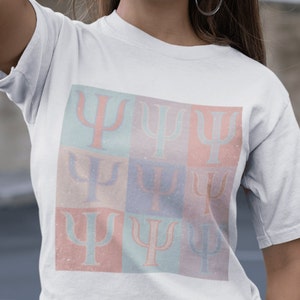 May include: White t-shirt with a colorful graphic print of nine repeated Greek letter psi symbols. The symbols are arranged in a 3x3 grid with each symbol in a different pastel color.