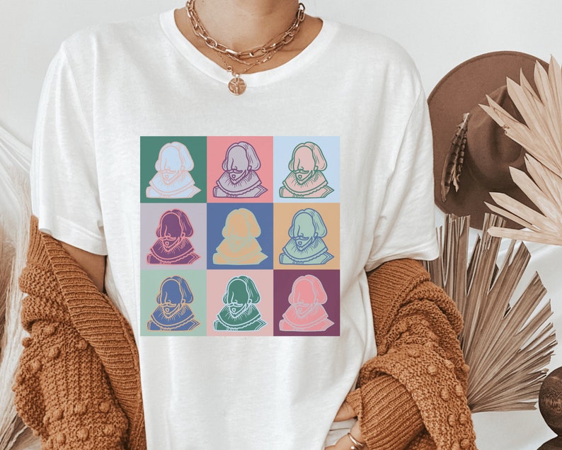Puede incluir: Camiseta blanca con un dise&ntilde;o de pop art colorido de un rostro de hombre repetido nueve veces.