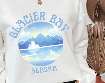 Peut inclure: Sweat-shirt blanc avec un graphique bleu et blanc d'une chaîne de montagnes et le texte "Glacier Bay Alaska" dans une police rétro.
