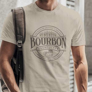 May include: A beige t-shirt with a circular graphic design featuring the text "Bourbon Kentucky" and the phrase "Too much of anything is bad, but too much bourbon is barely enough".