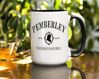 May include: White ceramic mug with a black handle. The mug has black text that reads "Pemberley Est. 1813 Derbyshire" with a silhouette of a person's head in a frame.