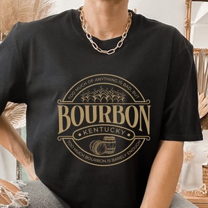May include: Black t-shirt with a gold graphic of a bourbon logo. The logo says "Too much of anything is bad, but Too much bourbon is barely enough." and "Bourbon Kentucky".