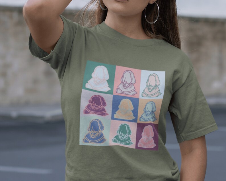 Puede incluir: Una camiseta verde con un estampado gr&aacute;fico colorido de nueve retratos de una persona con barba y un cuello de encaje. Los retratos est&aacute;n dispuestos en una cuadr&iacute;cula de 3x3.