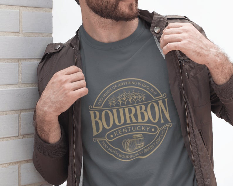May include: A dark gray t-shirt with a gold graphic of a bourbon barrel and the text "Too much of anything is bad, but Too much bourbon is barely enough. Kentucky."