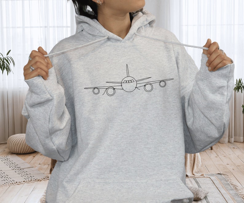 以下が含まれることがあります： 前面に飛行機のシンプルな線画が描かれたグレーのパーカー