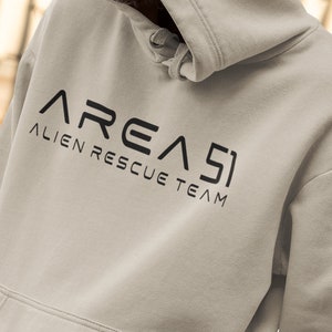 May include: A light gray hoodie with a black graphic that says "AREA 51" and "ALIEN RESCUE TEAM" in a stylized font.