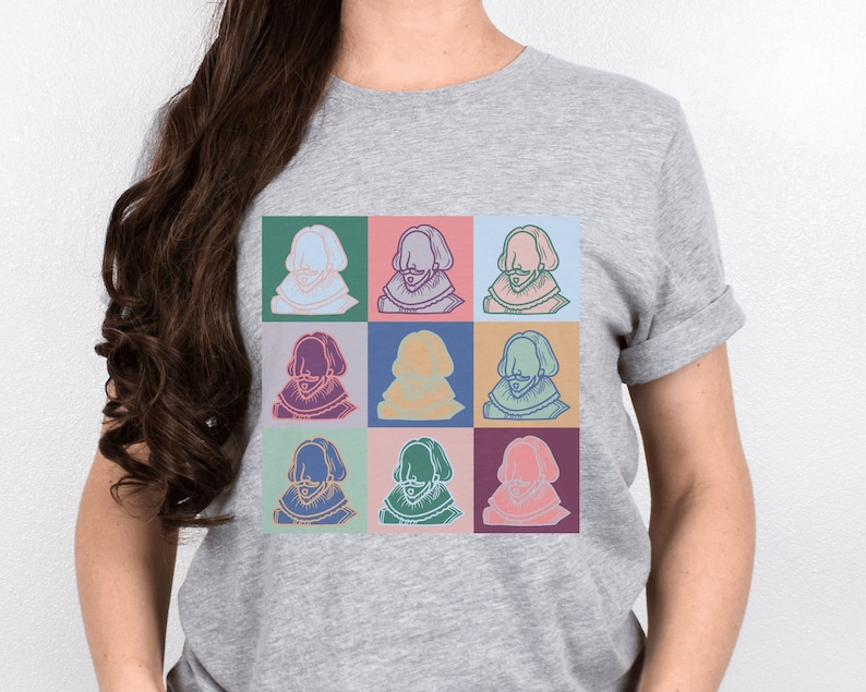 Puede incluir: Una camiseta gris con un dise&ntilde;o de pop art colorido que presenta una imagen repetida de un hombre con barba y un cuello de encaje.