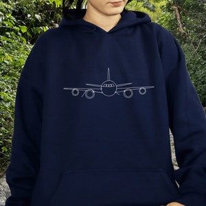 以下が含まれることがあります： 前面に飛行機の白いアウトラインが描かれたネイビーブルーのパーカー