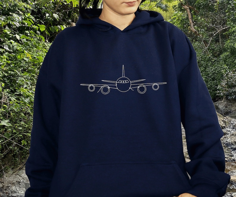 以下が含まれることがあります： 前面に飛行機の白いアウトラインが描かれたネイビーブルーのパーカー