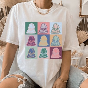 Puede incluir: Camiseta blanca con un estampado gr&aacute;fico colorido de un rostro de hombre repetido nueve veces en un patr&oacute;n de cuadr&iacute;cula.