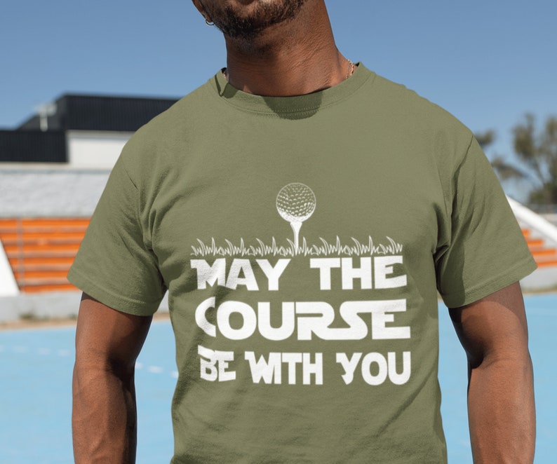 May include: A green t-shirt with a white golf ball graphic and the text "May the Course Be With You".