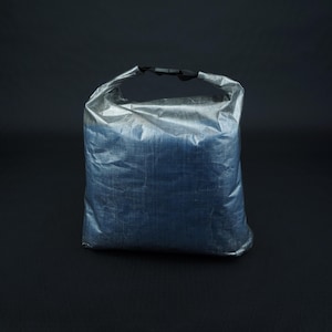 Könnte beinhalten: Eine silberne Trockenbeutel mit einem schwarzen Griff. Die Tasche ist aus wasserdichtem Material gefertigt und soll Gegenstände trocken halten.