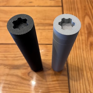 May include: Two cylindrical objects with a star-shaped opening at the top. One is black and the other is gray.