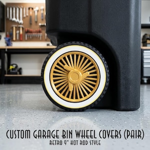 May include: Black garage bin with a retro-style wheel cover. The wheel has a gold-colored spoke design with a white outer ring and a black tire. The text at the bottom reads "CUSTOM GARAGE BIN WHEEL COVERS (PAIR) RETRO 9" HOT ROD STYLE."
