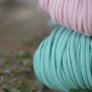 Op de afbeelding: Twee spoelen garen, één lichtroze en één lichtblauw, liggen op elkaar.