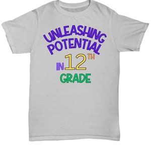 May include: A light gray t-shirt with the text "UNLEASHING POTENTIAL IN 12TH GRADE" in a rainbow of colors.
