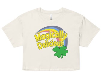 May include: A white cropped t-shirt with a rainbow and the text "Magically Delicious" in yellow. A green four-leaf clover is below the text.
