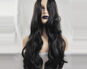 May include: A long, wavy black wig displayed on a mannequin head. The wig features a natural-looking part and voluminous, flowing curls. The mannequin has pale skin and dark lipstick, set against a white backdrop.