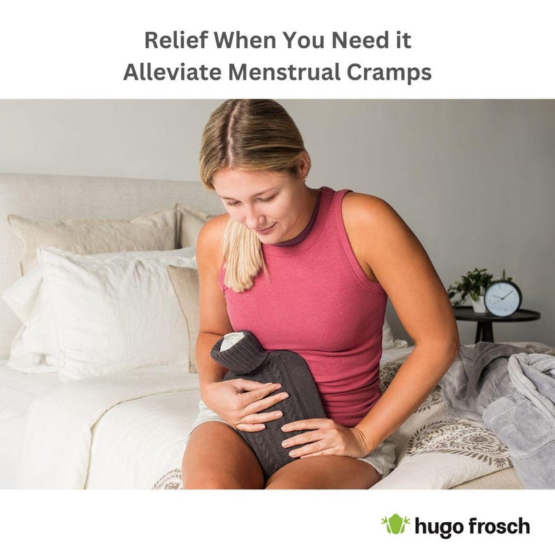 May include: A woman sits on a bed holding a gray knitted hot water bottle against her abdomen. The text "Relief When You Need It Alleviate Menstrual Cramps" is at the top of the image. The text "hugo Frosch" is at the bottom of the image.