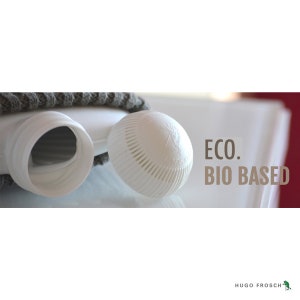 Puede incluir: Botella de agua caliente de pl&aacute;stico blanco con una cubierta de punto gris. La botella tiene una tapa de rosca y un pico. El texto "ECO. BIO BASED" est&aacute; impreso en la imagen.