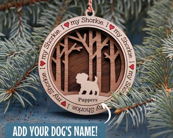 May include: A wooden Christmas ornament featuring a silhouette of a dog in a forest scene. The ornament is three-layered and has the text "I my Shorkie. I my Shorkie. I my Shorkie. I my Shorkie" around the edge. The dog is labeled "Puppers".