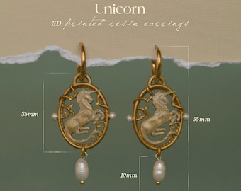 May include: Gold-coloured 3D printed resin earrings. Each earring features an oval pendant with a unicorn design, a pearl accent, and a dangling pearl. The earrings are 5.5cm long, 3.5cm wide, and the pearl is 1cm.
